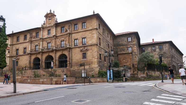 Ein großes historisches Steingebäude steht an einer Straße im Zentrum von Oviedo.
