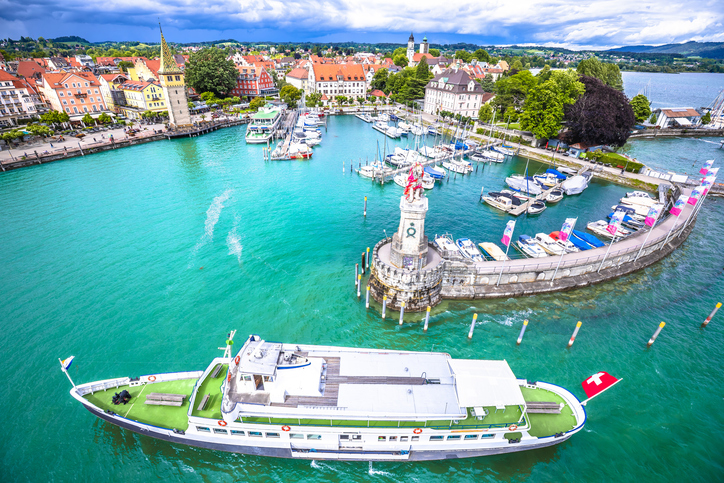 Ein großes Ausflugsschiff fährt in den Hafen ein, im Hintergrund sieht man die Hafeneinfahrt mit der berühmten Löwenstatue und dem Leuchtturm