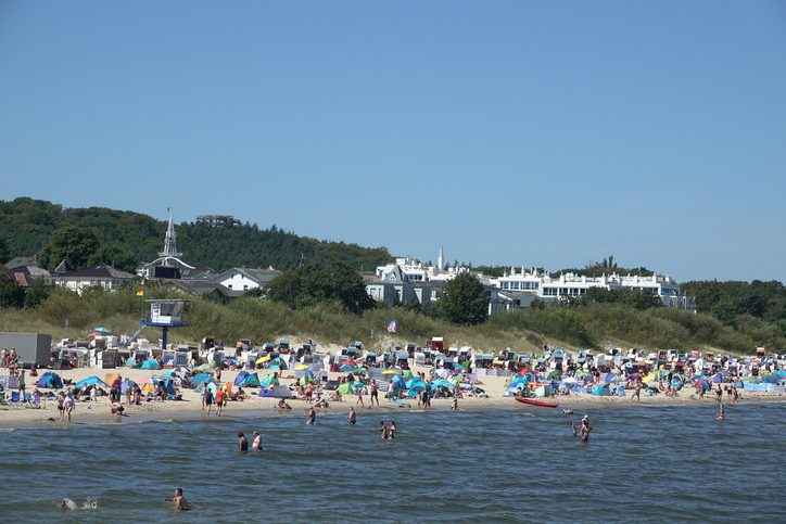Ein voller Strand mit vielen Badegästen und bunten Sonnenschirmen an einem sonnigen Tag in Ahlbeck.