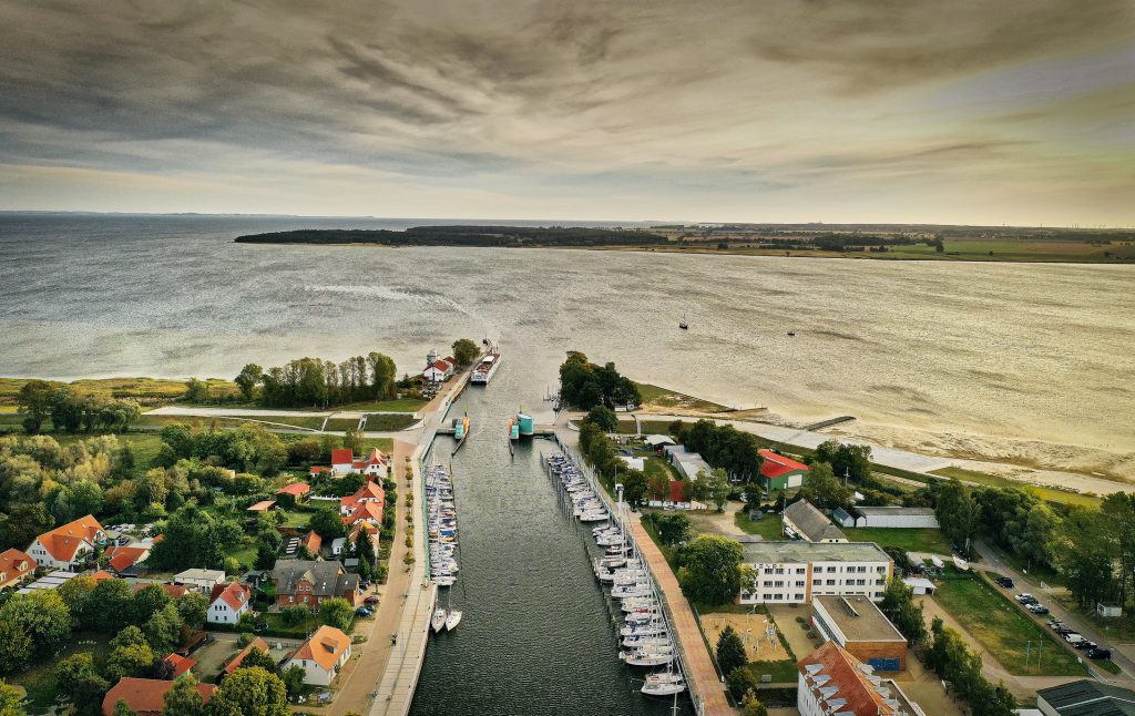 Eine Drohnenaufnahme zeigt die Einfahrt des Greifswalder Hafens, die in die weitläufige Wasserfläche des Greifswalder Boddens übergeht.