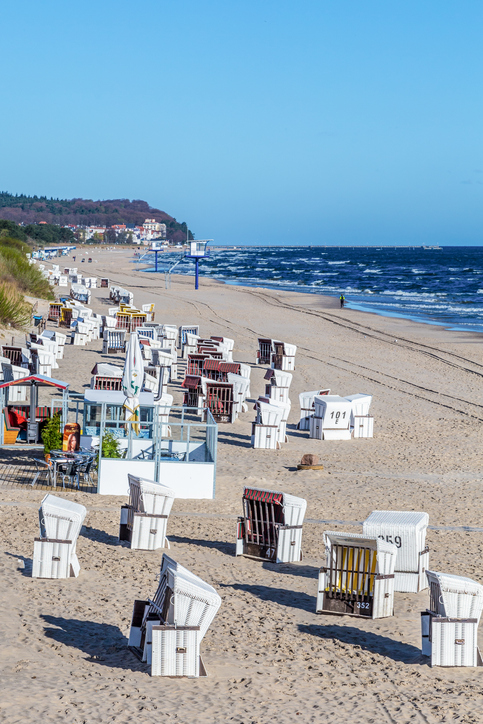 Zahlreiche weiße Strandkörbe stehen ordentlich aufgereiht auf dem breiten Sandstrand in Ahlbeck.