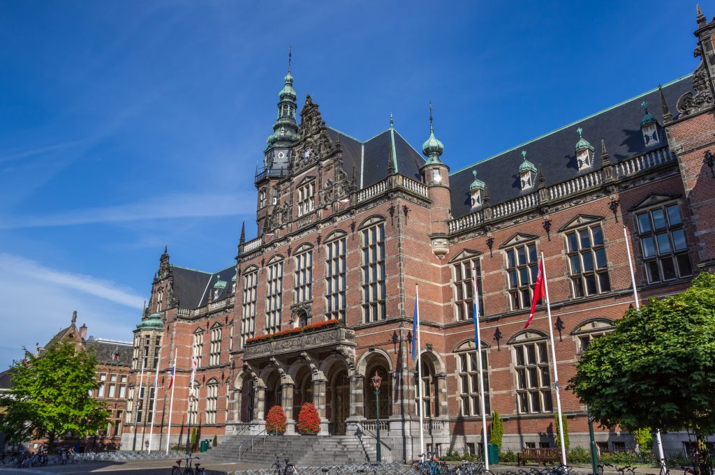 Das historische, in rotem Backstein erbaute Akademiegebäude der Universität von Groningen bei strahlendem Sonnenschein.