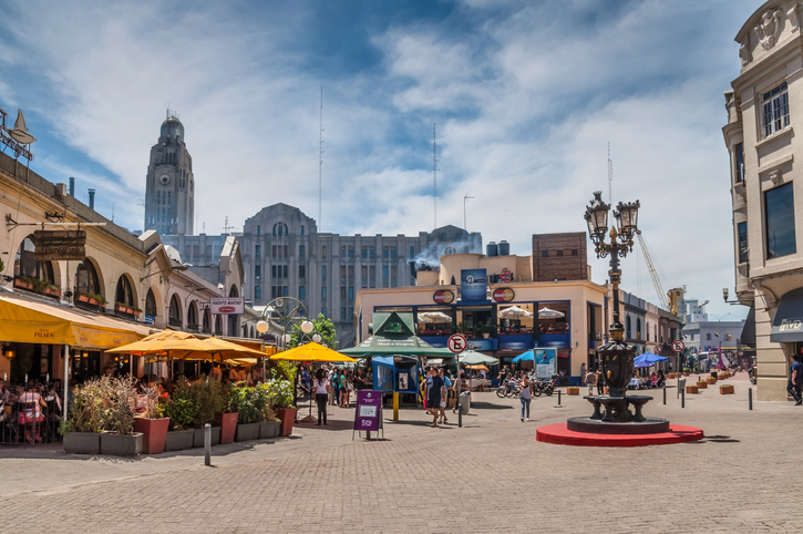 Ein belebter Platz in der Altstadt von Montevideo mit Restaurants und historischen Gebäuden im Hintergrund.