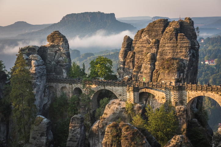 Die berühmte Basteibrücke spannt sich zwischen hohen Felsen in der Sächsischen Schweiz.