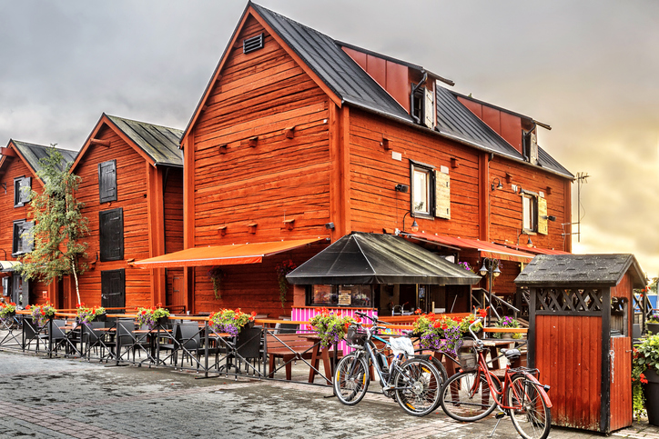 Traditionelle rote Holzgebäude mit einer Terrasse voller Blumen und Fahrrädern im Vordergrund.