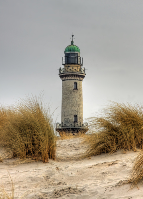Der ikonische Leuchtturm von Warnemünde, eingerahmt von sandigen Dünen und Dünengras.