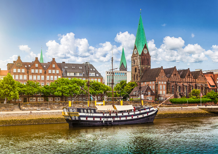 Ein großes, historisches Segelschiff liegt auf der Weser vor der Kulisse der Bremer Altstadt und der markanten Turmspitzen.