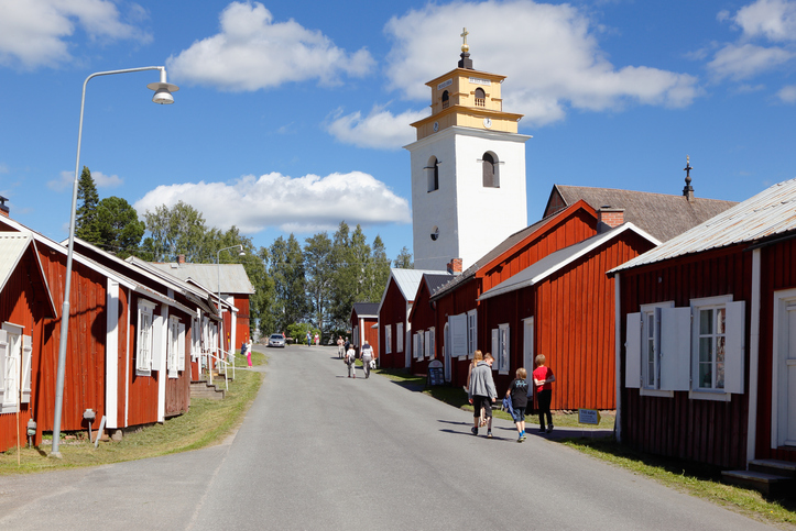Historische rote Holzhäuser und eine weiße Kirche in Gammelstad bei Luleå.