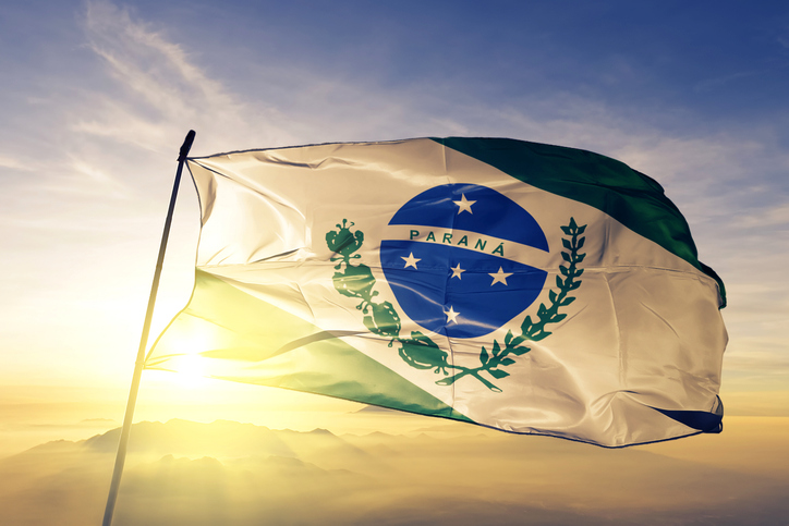 Die Flagge von Paraná weht im warmen Licht vor einer weiten Landschaft.