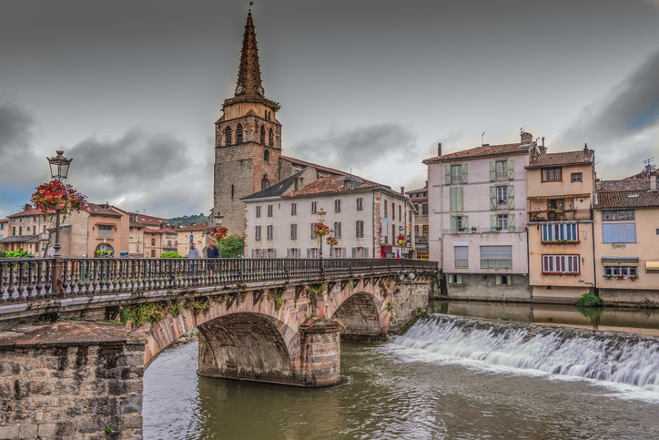 Historische Steinbrücke mit Blumen, Flusswehr und Kirche im Zentrum von Saint-Girons