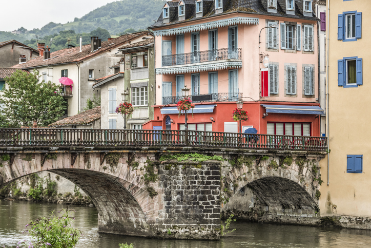 Alte Brücke über den Fluss mit farbigen Häusern und Blumenschmuck in Saint-Girons