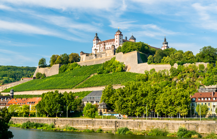Die Festung Marienberg thront oberhalb des Mains über Weinbergen und grünen Hängen in Würzburg.