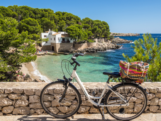 Fahrrad vor einer Bucht mit klarem Wasser in Cala Gat auf Mallorca