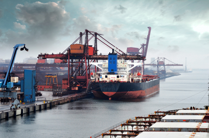 Ein großes Frachtschiff liegt zwischen Kränen und Hafenanlagen im Industriehafen von Dunkerque.