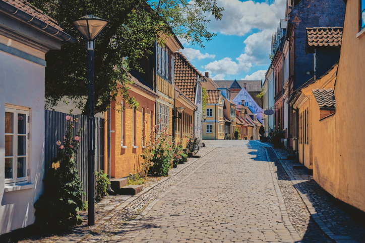 Eine stille Kopfsteinpflastergasse mit gelben Häusern und historischen Fassaden führt durch Odense.