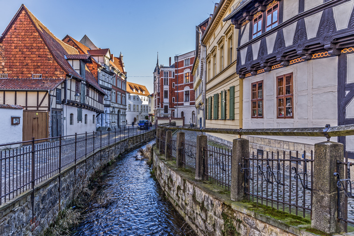 Eine historische Gasse mit Fachwerkhäusern und kleinem Wasserlauf führt durch Quedlinburg.