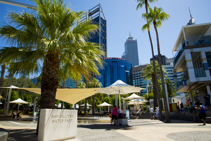 Palmen, Sitzbereiche und moderne Gebäude am Elizabeth Quay in Perth mit Hochhäusern im Hintergrund.