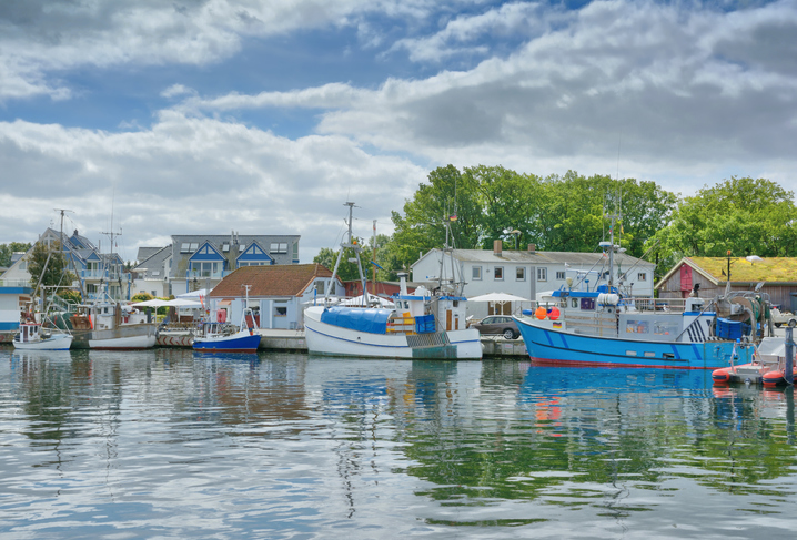Kleine Fischerboote und Häuser am ruhigen Hafen bei Timmendorfer Strand an der Ostsee.