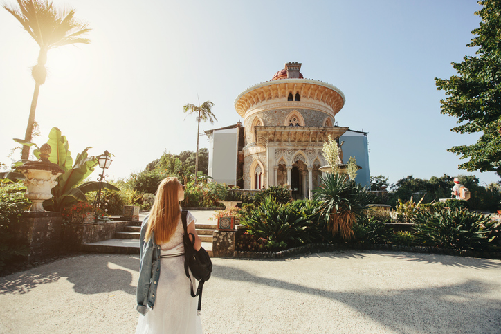 Eine Besucherin steht vor dem kunstvollen Palácio de Monserrate in Sintra bei sonnigem Wetter.