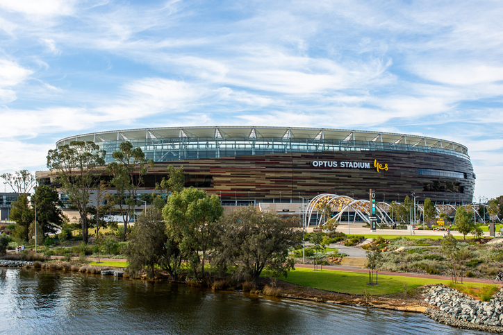 Das Optus Stadium in Perth am Wasser mit moderner Architektur und Grünflächen im Vordergrund.