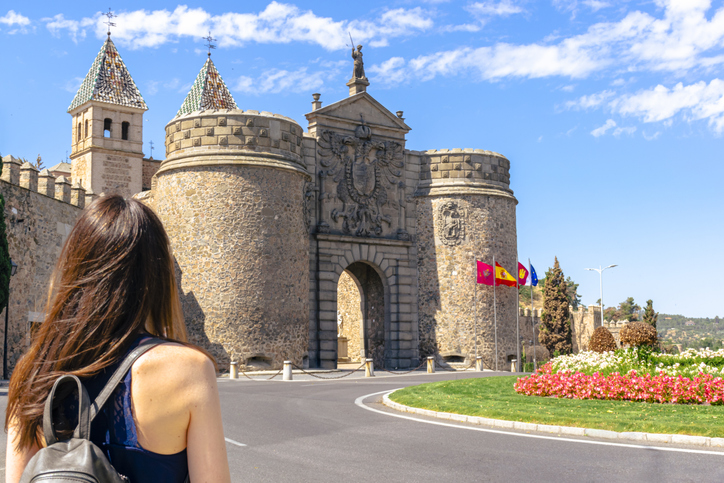 Reisende vor der Puerta de Bisagra mit steinernen Türmen und Stadtwappen in Toledo