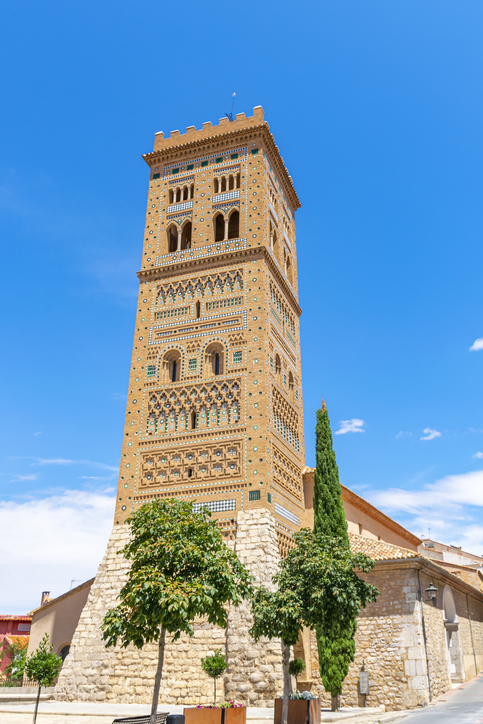 Hoher verzierter Backsteinturm im Mudéjar-Stil in einer Straße von Teruel