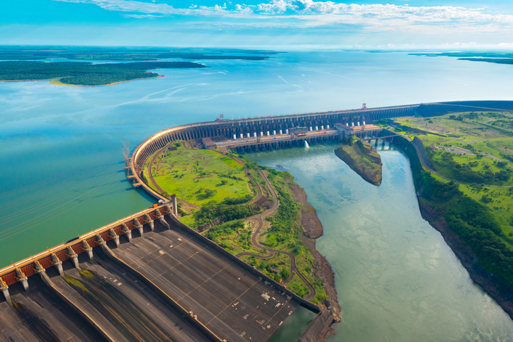 Der riesige Itaipu-Staudamm liegt zwischen Wasserflächen und grüner Landschaft in Paraná.