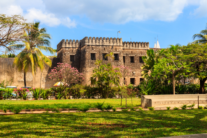 Ein historisches Steingebäude mit Palmen und Grünanlage steht in Stone Town auf Sansibar.