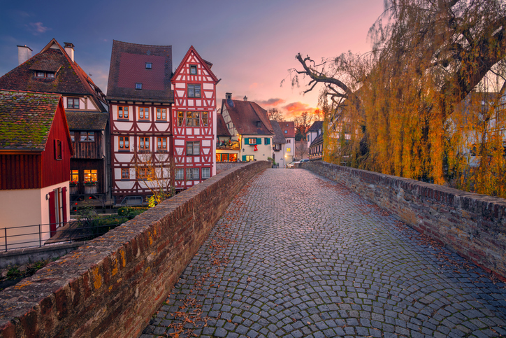 Gepflasterte Brücke im Fischerviertel in Ulm, umgeben von Fachwerkhäusern und herbstlicher Abendstimmung.