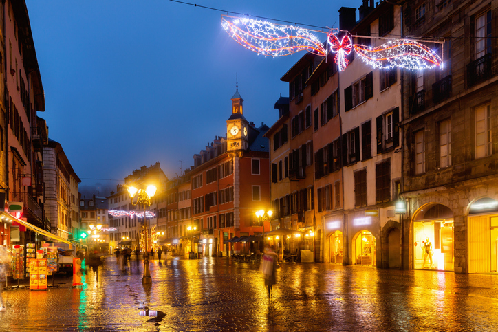 Historische Einkaufsstraße mit Weihnachtsbeleuchtung und Uhrturm in Chambéry