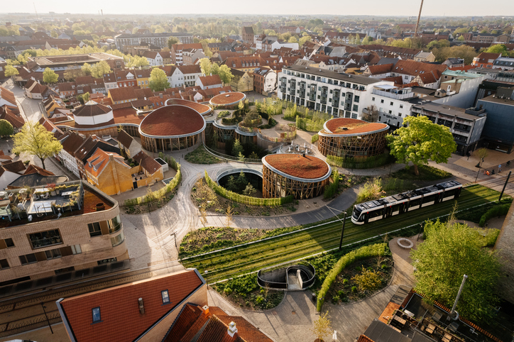 Luftaufnahme von Odense mit moderner Museumsarchitektur, begrünten Wegen und Stadtbahn.