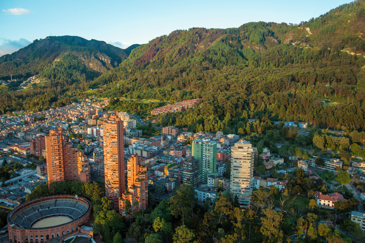 Luftaufnahme von Bogotá mit Hochhäusern, Stierkampfarena und bewaldeten Bergen
