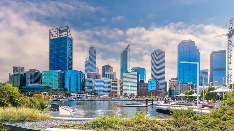 Blick auf die Skyline von Perth mit modernen Hochhäusern, Wasser und begrünten Uferbereichen.