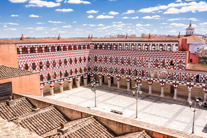 Großer Innenhof mit rot-weiß gemusterter Fassade und Arkaden in der Region Badajoz