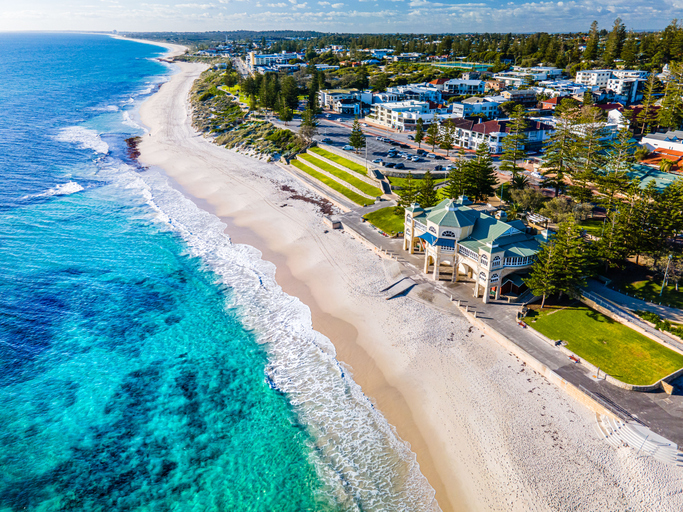 Luftbild einer Küstenlinie bei Perth mit hellem Strand, türkisfarbenem Wasser und Häusern entlang der Küste.