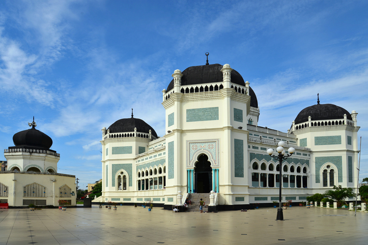 Die Große Moschee von Medan zeigt weiße Fassaden, schwarze Kuppeln und orientalische Architektur.