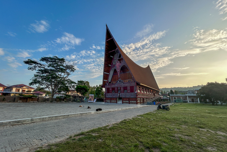 Ein großes traditionelles Batak-Haus mit geschwungenem Dach steht in der Umgebung von Medan.