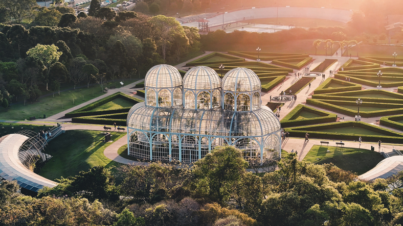 Das gläserne Gewächshaus im Botanischen Garten von Curitiba steht in einer gepflegten Parkanlage.