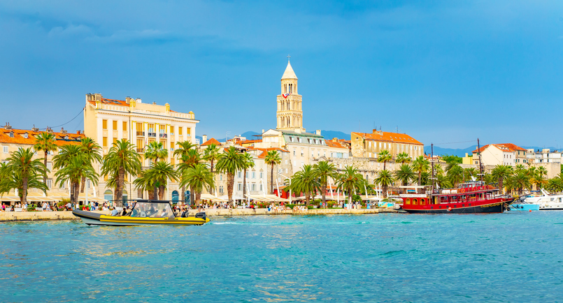Die Riva von Split mit Palmen, Booten, Wasser und Blick auf die Altstadt und den Glockenturm.
