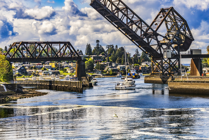 Eine geöffnete Klappbrücke überspannt einen Wasserweg mit Segelbooten in Seattle.