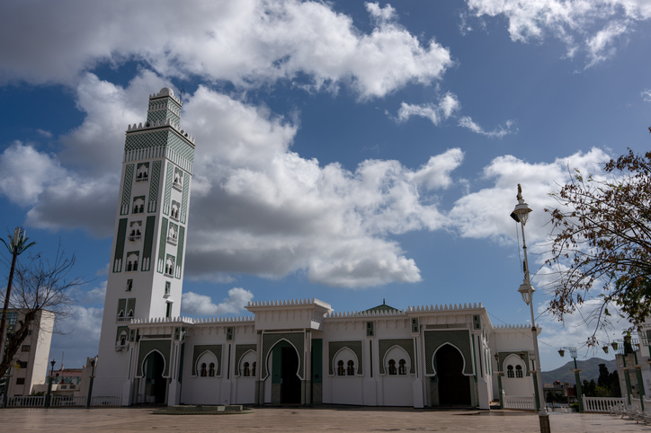 Weiße Moschee mit hohem Minarett unter blauem Himmel in Tetouan
