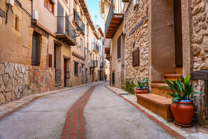 Schmale gepflasterte Straße mit Natursteinfassaden und traditionellen Häusern in Teruel