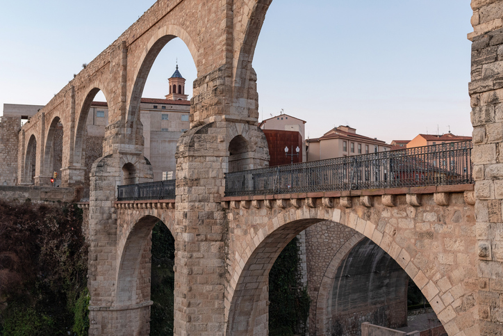 Alte Brücke mit großen Steinbögen über einem tiefen Einschnitt in der Stadt