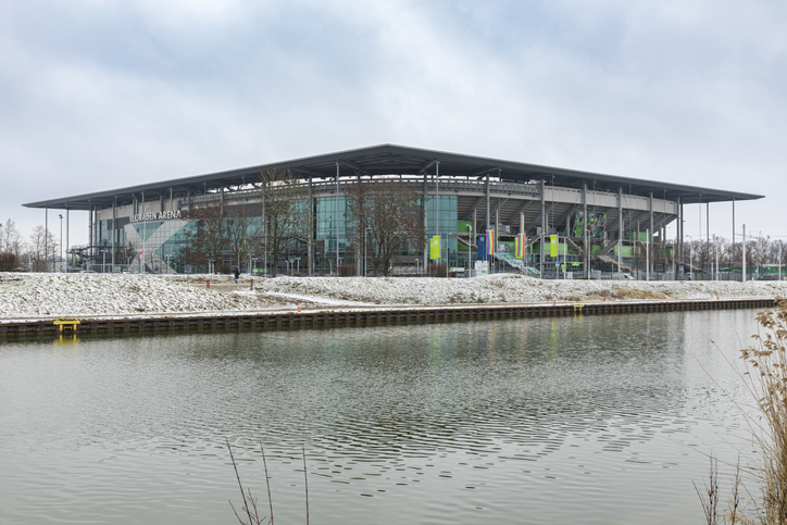 Die Volkswagen Arena in Wolfsburg am Wasser mit moderner Stadionarchitektur und winterlicher Umgebung.