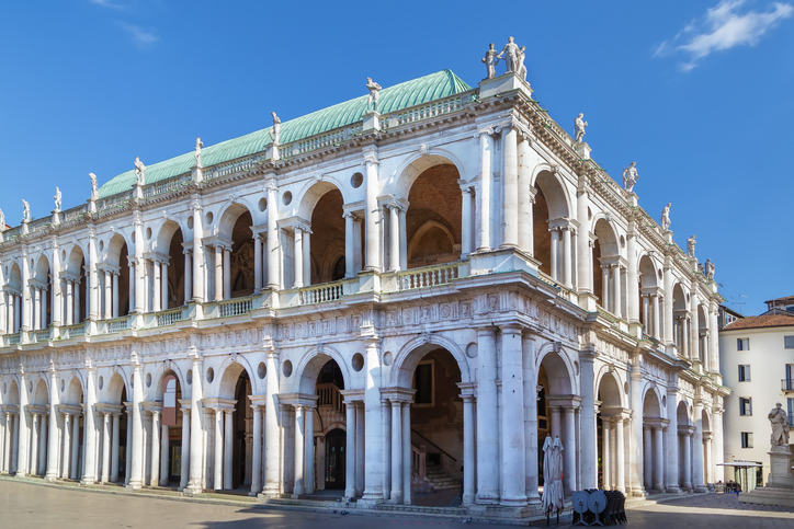 Die Basilica Palladiana in Vicenza beeindruckt mit weißen Arkaden, Säulen und grünem Dach.