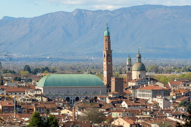 Blick über Vicenza mit Basilica Palladiana, Torre Bissara, roten Dächern und Bergen im Hintergrund.