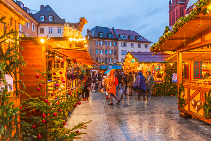 Festlich geschmückte Marktstände und Besucher auf dem Weihnachtsmarkt in Würzburg am Abend.