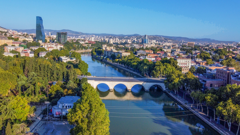 Luftaufnahme von Saarbrücken mit Fluss, Brücke, vielen Bäumen und weitem Blick über die Stadt.