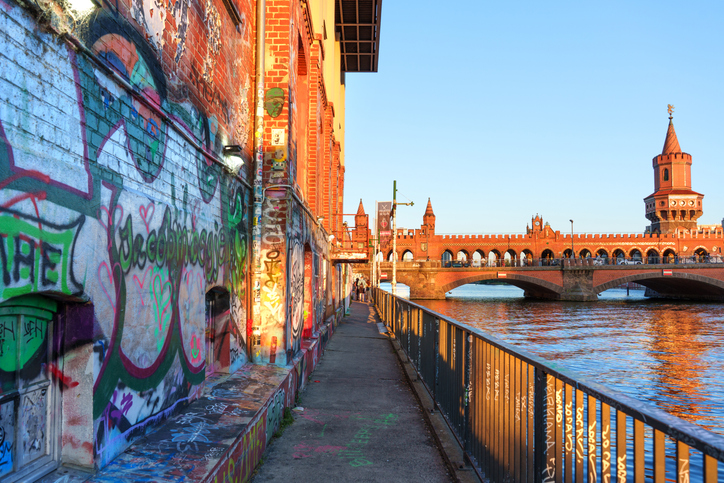 Graffiti am Spreeufer und die Oberbaumbrücke prägen eine urbane Szene in Berlin.