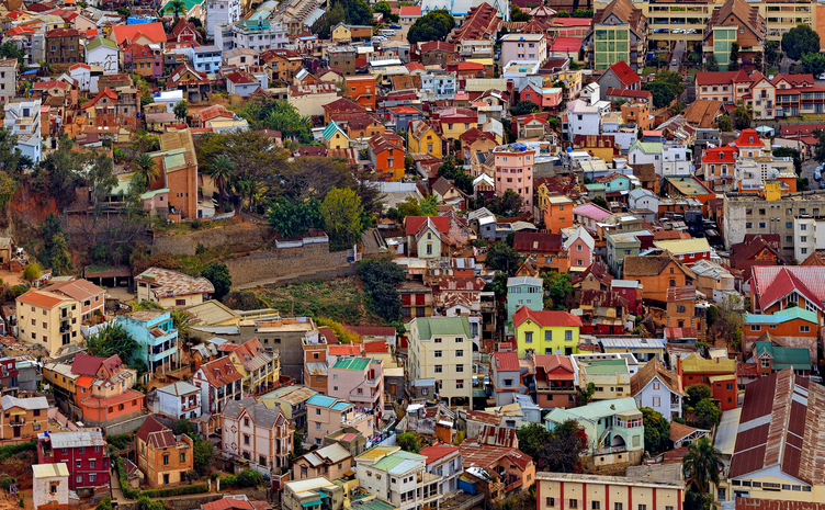 Nahaufnahme vieler dicht aneinander gebauter, farbiger Häuser in einem Stadtviertel von Antananarivo.